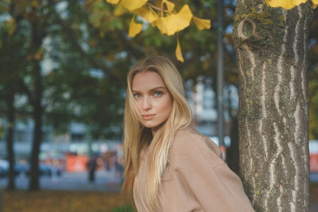 portrait of blonde woman wearing coat in park